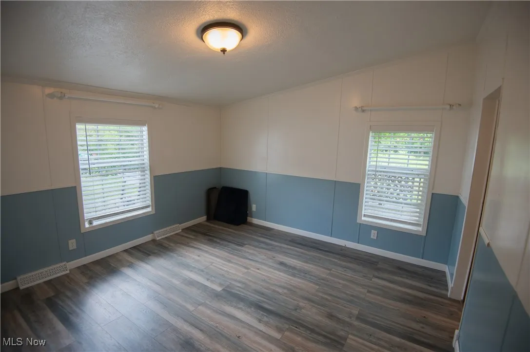 Spare room with dark wood-type flooring, a textured ceiling, and crown molding