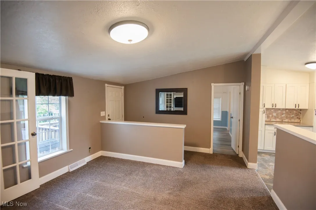 Unfurnished room with lofted ceiling and dark colored carpet