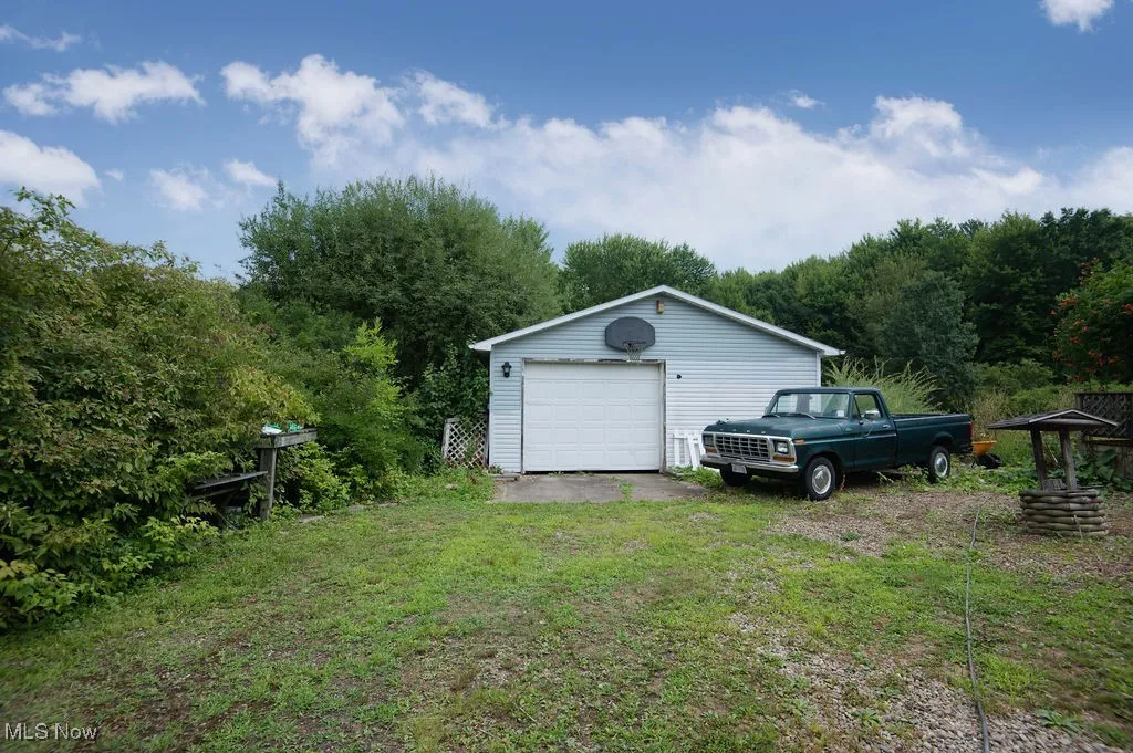 Detached garage with driveway and a view of trees