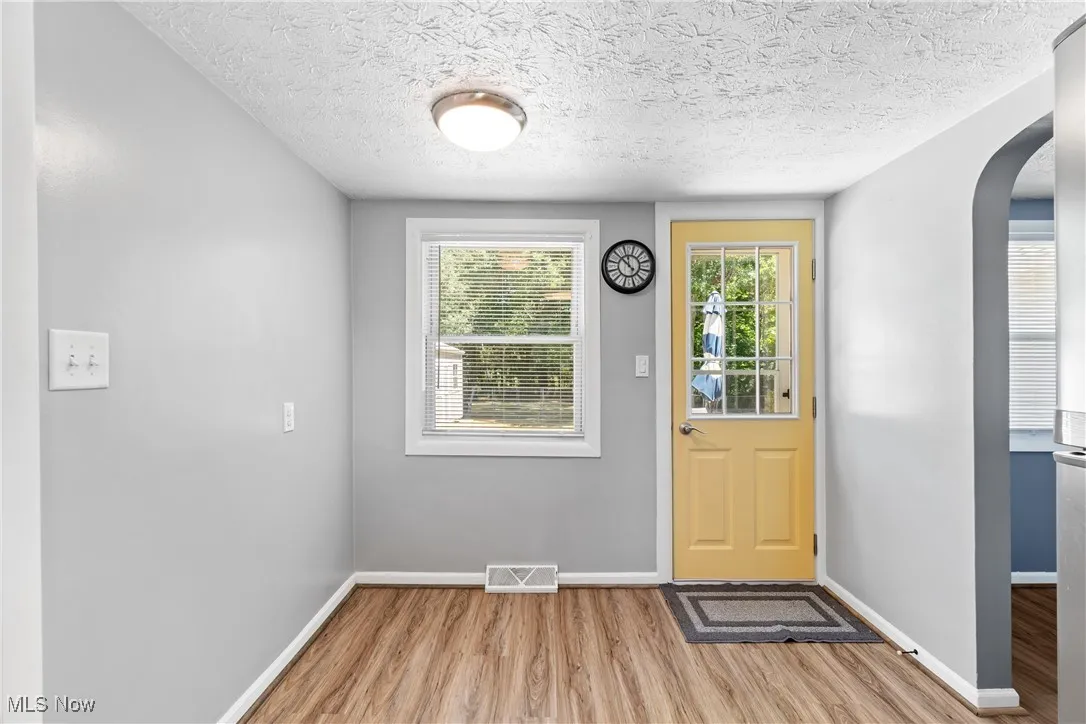 Doorway to patio, finished floors, and a textured ceiling