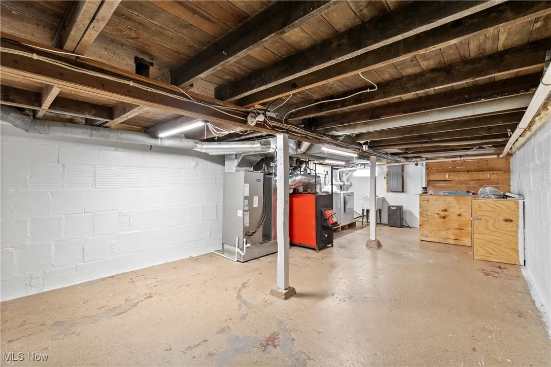 Unfinished basement featuring heating unit and electric panel