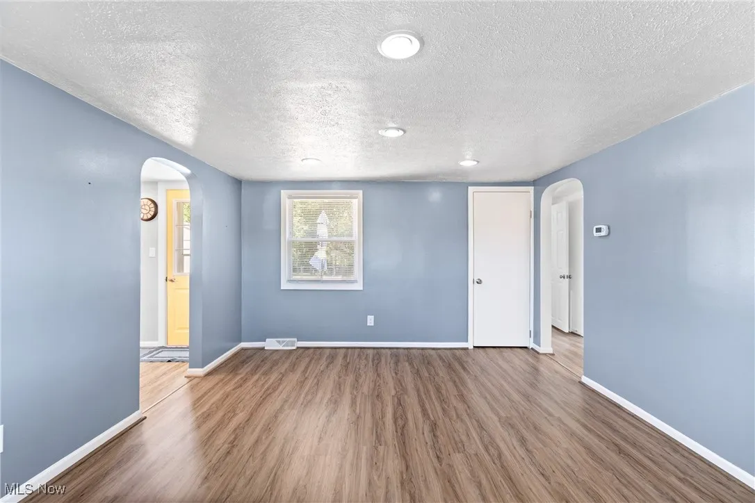 Living room featuring arched walkways, dark wood finished floors, and a textured ceiling