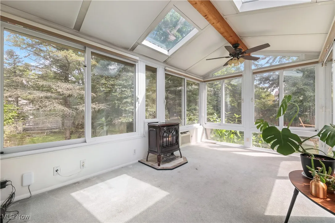 Sunroom featuring a wood stove, carpet floors, and a skylight