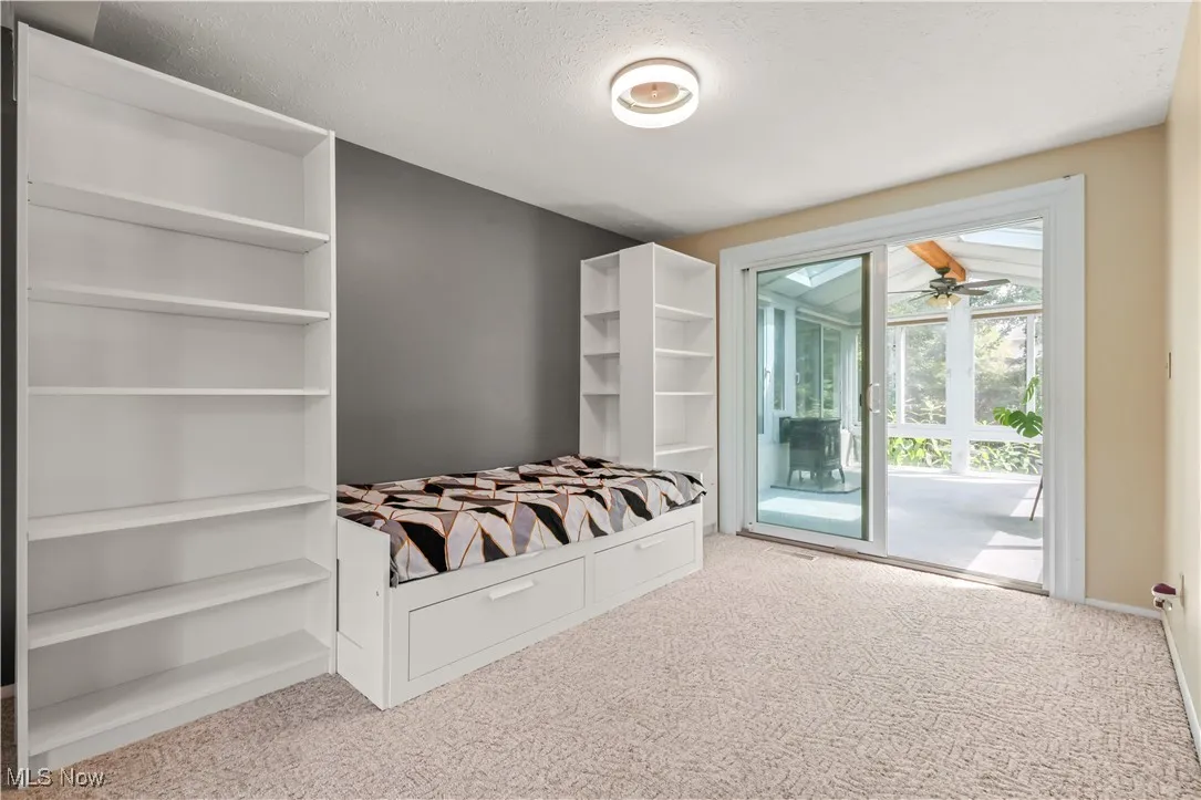 Unfurnished bedroom featuring carpet floors, access to exterior, and a textured ceiling