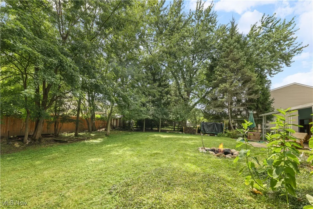 Fenced backyard featuring a trampoline and a fire pit