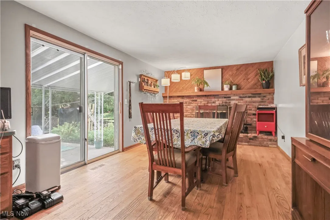 Dining space with light wood-style flooring, a textured ceiling, and wood walls