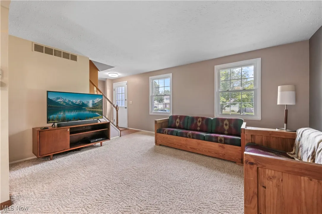 Carpeted living area featuring a textured ceiling and stairs