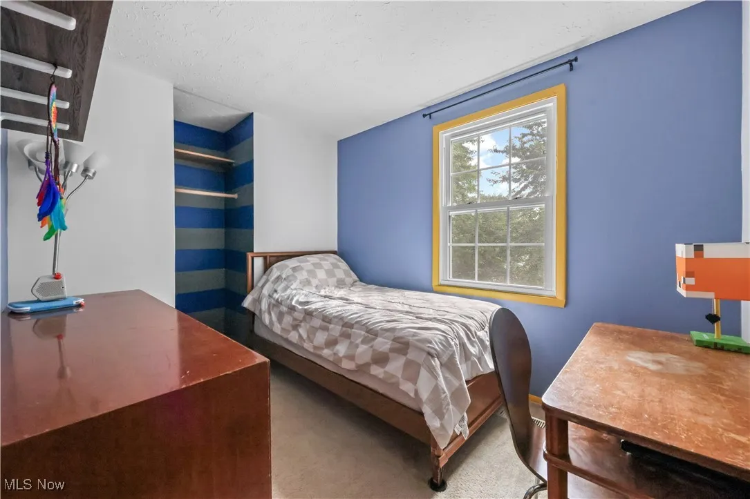 Bedroom with a desk, a textured ceiling, and carpet