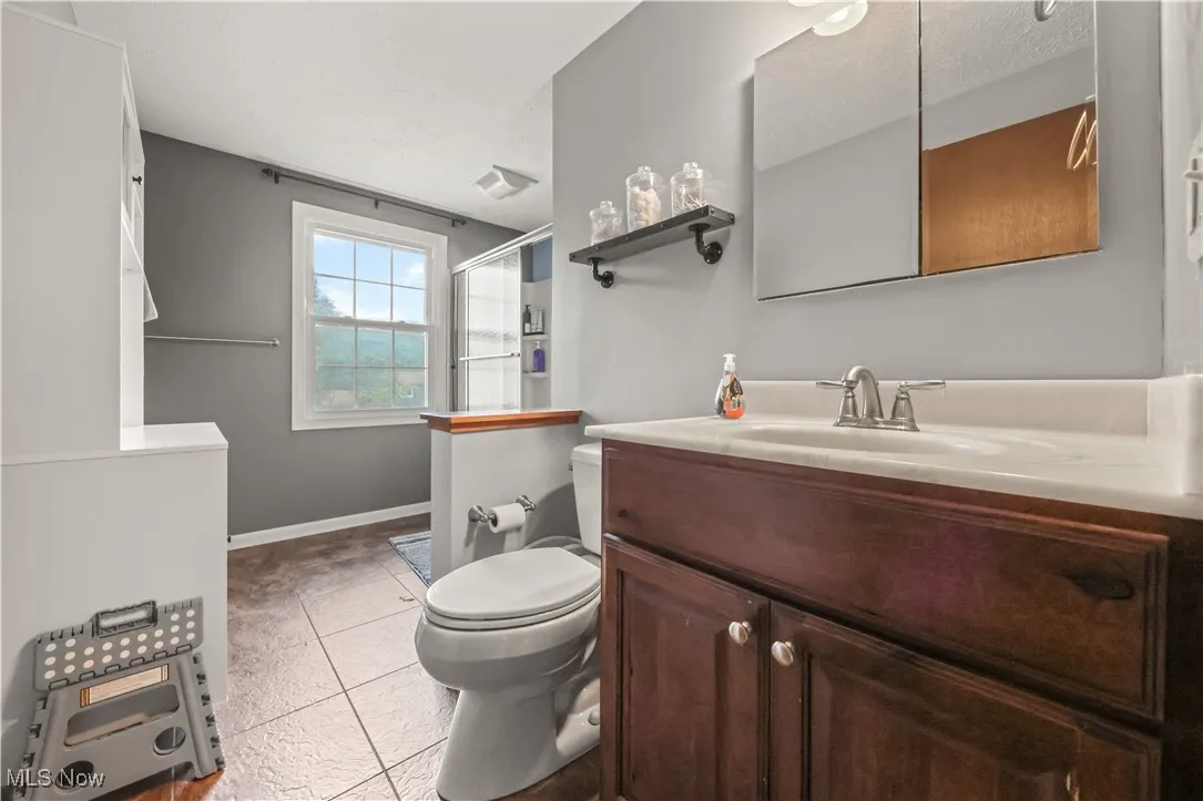 Full bathroom featuring light tile patterned floors, vanity, and a stall shower
