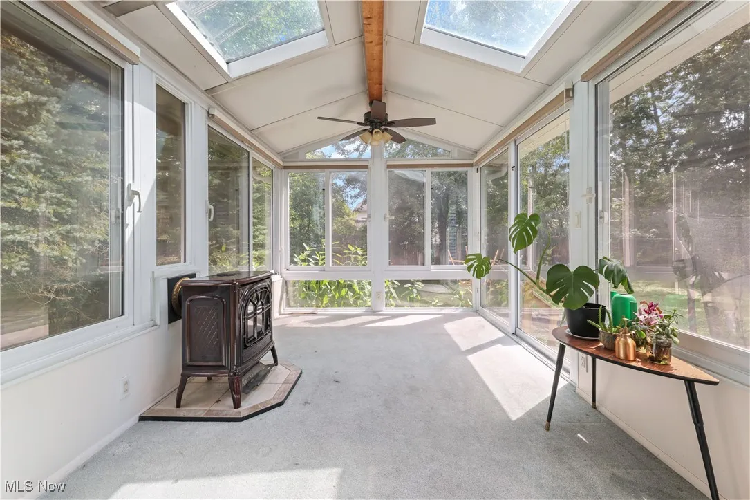 Sunroom featuring plenty of natural light, a wood stove, and a skylight