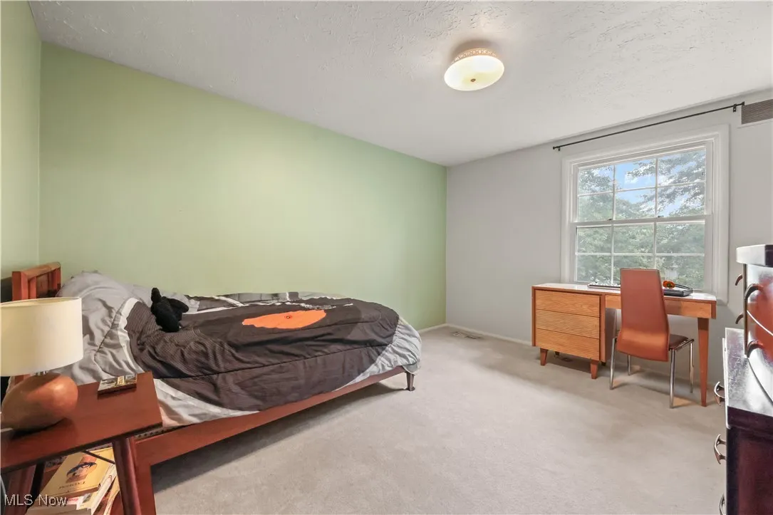 Carpeted bedroom with an office area and a textured ceiling