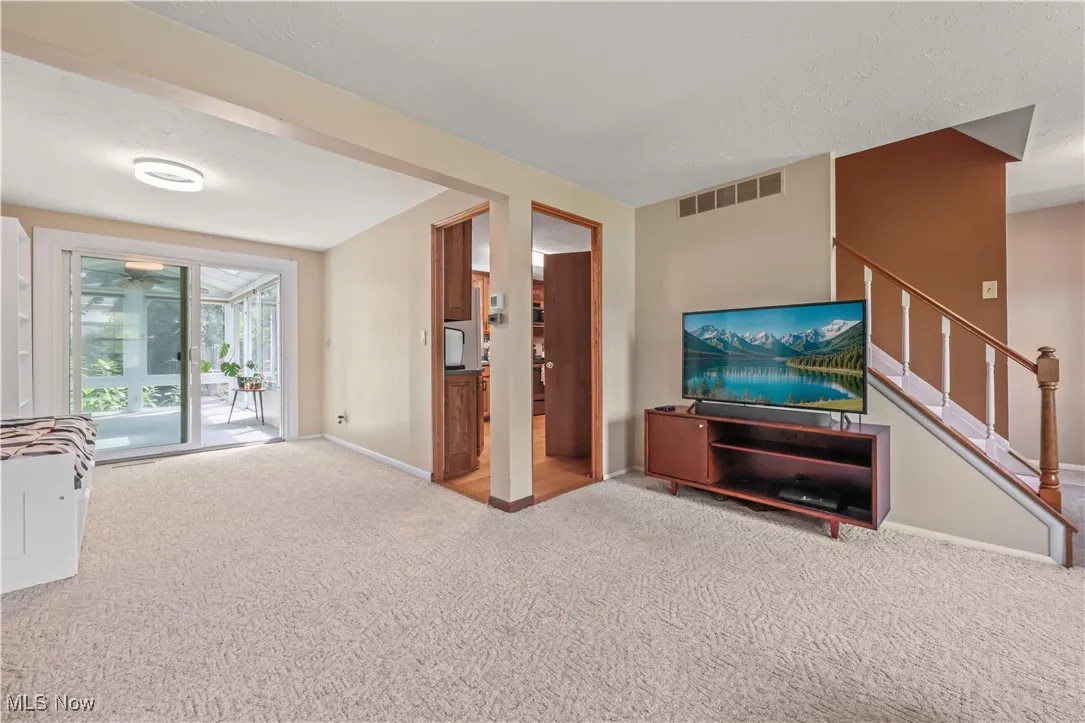 Unfurnished living room with carpet flooring and stairway