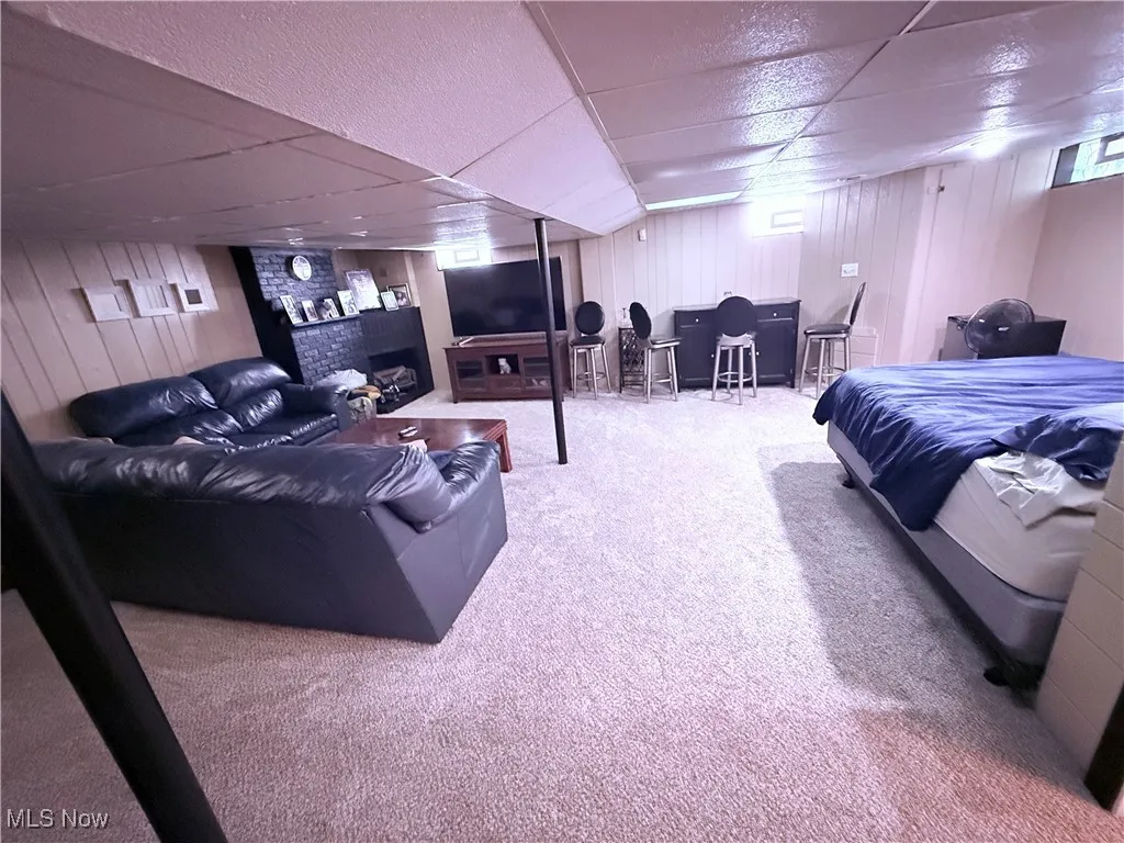 Bedroom with a paneled ceiling, carpet flooring, and wooden walls