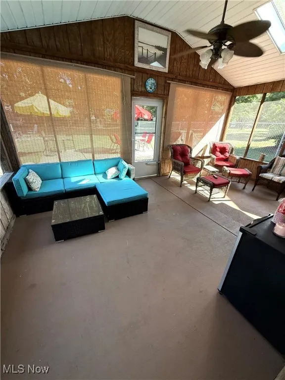 Sunroom with wooden walls, lofted ceiling, and concrete flooring