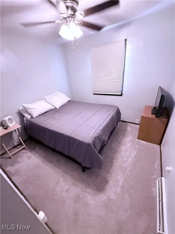 Carpeted bedroom featuring a ceiling fan