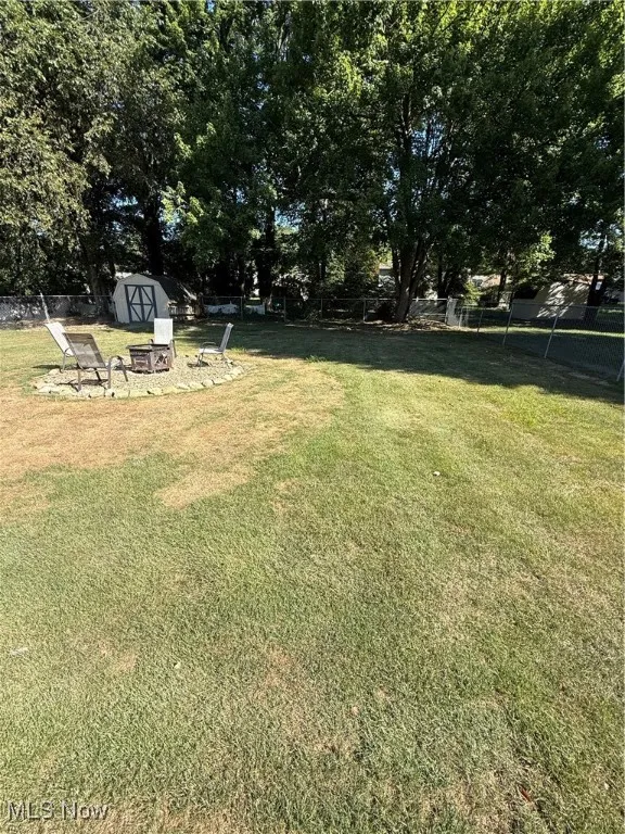 View of yard featuring a shed, a fire pit, and a patio area