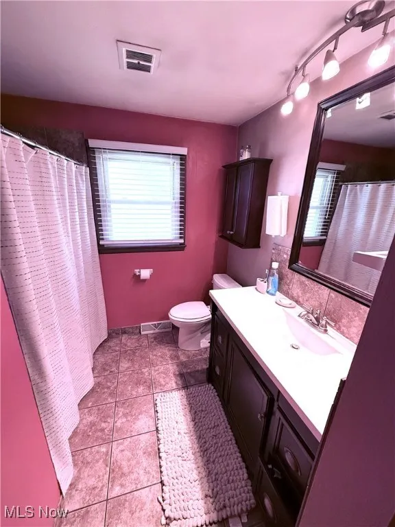 Bathroom with vanity, light tile patterned floors, curtained shower, and tasteful backsplash