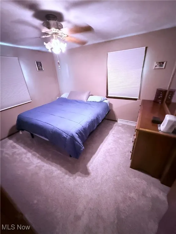 Carpeted bedroom featuring a ceiling fan and baseboards