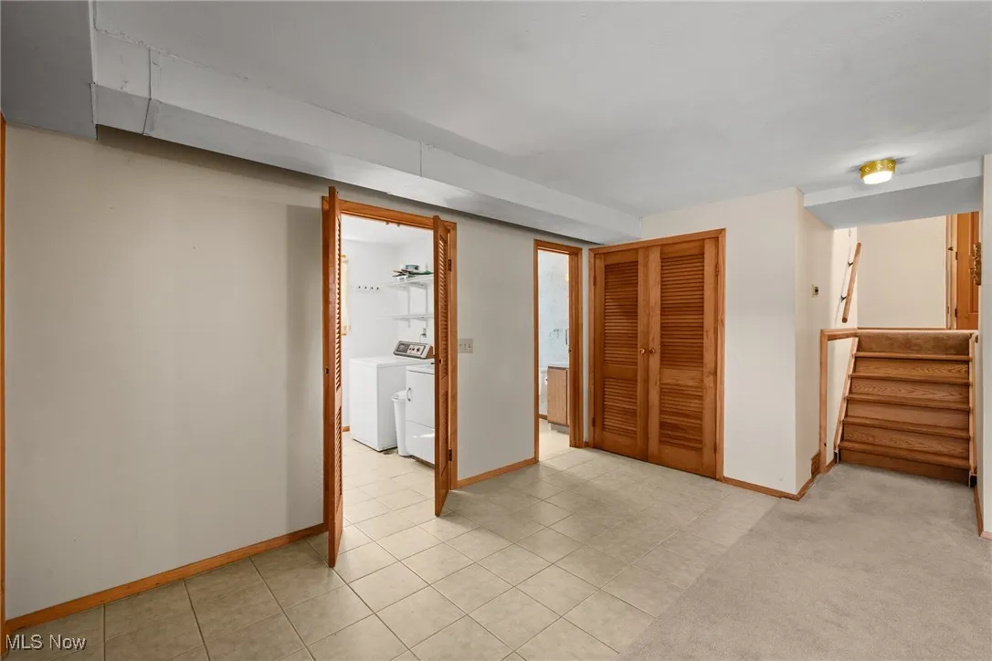 Unfurnished bedroom with a closet, washer and dryer, and light tile patterned floors