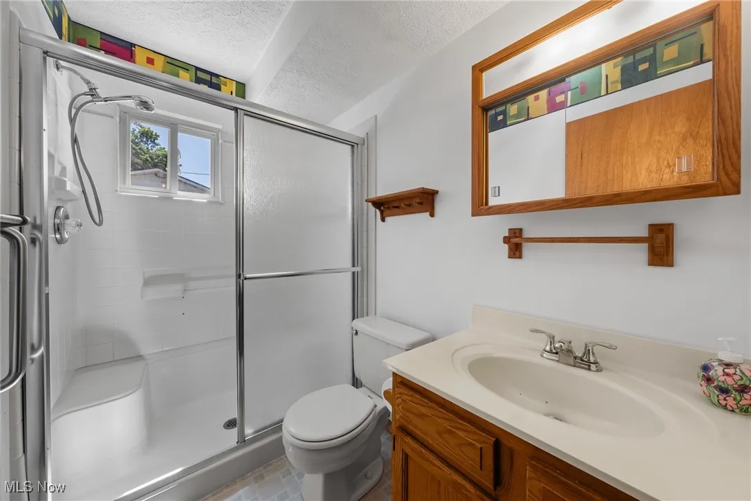 Full bathroom with a shower stall, a textured ceiling, and vanity