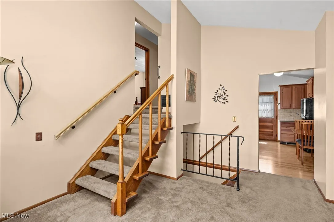 Stairs with carpet floors and lofted ceiling