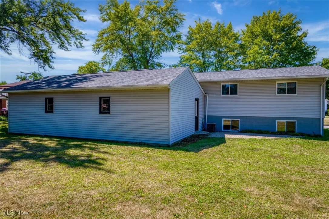 Rear view of property with a yard and a shingled roof