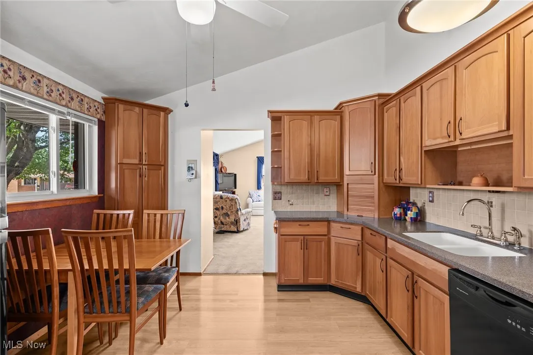 Kitchen with open shelves, lofted ceiling, dishwasher, backsplash, and light wood-style floors