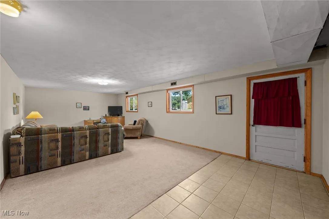 Living area with light carpet, light tile patterned floors, and a textured ceiling