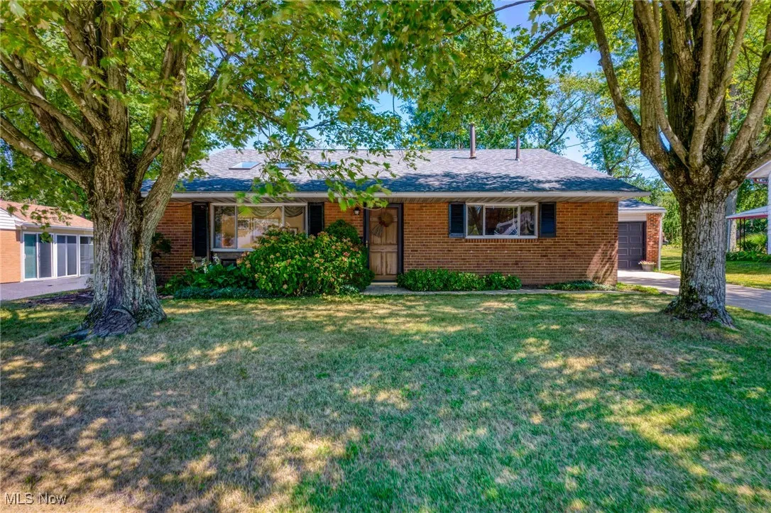 Single story home featuring brick siding, a front yard, and a shingled roof