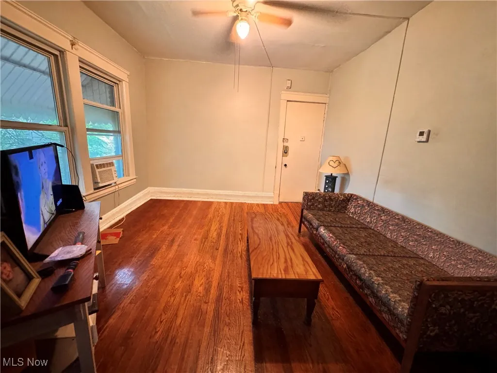 unit 4 Living area with wood finished floors, ceiling fan, and cooling unit