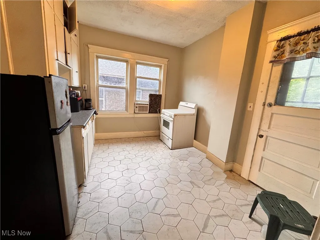 unit 4 Kitchen with freestanding refrigerator, white range, a textured ceiling, white cabinetry, and cooling unit
