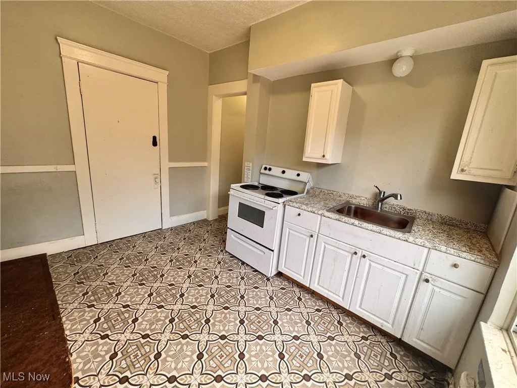 Unit 3 Kitchen featuring white electric range, white cabinetry, and a textured ceiling
