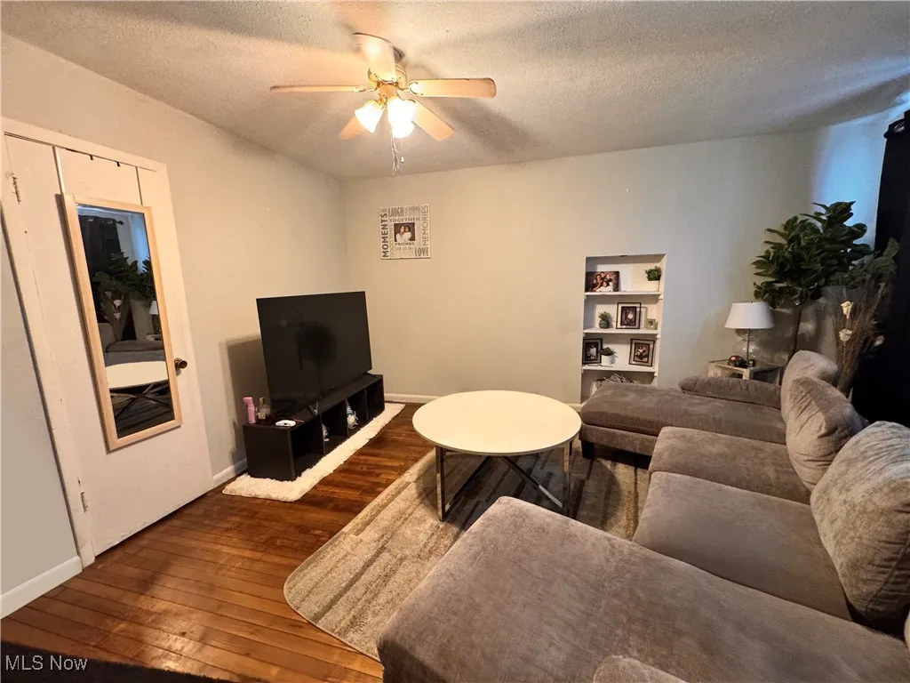 Unit 1 Living area with a textured ceiling, dark wood finished floors, and ceiling fan