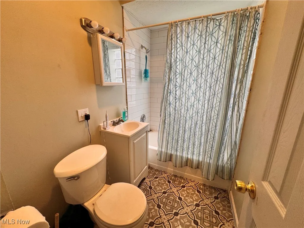 unit 3 Bathroom featuring shower / bathtub combination with curtain, vanity, and tile patterned floors