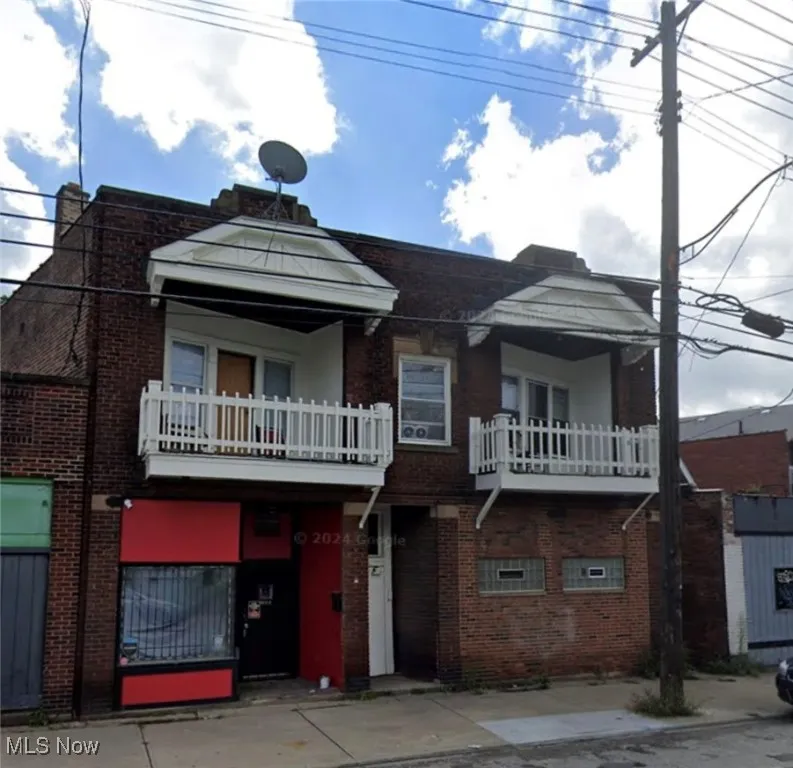 View of front of home featuring a balcony and brick siding