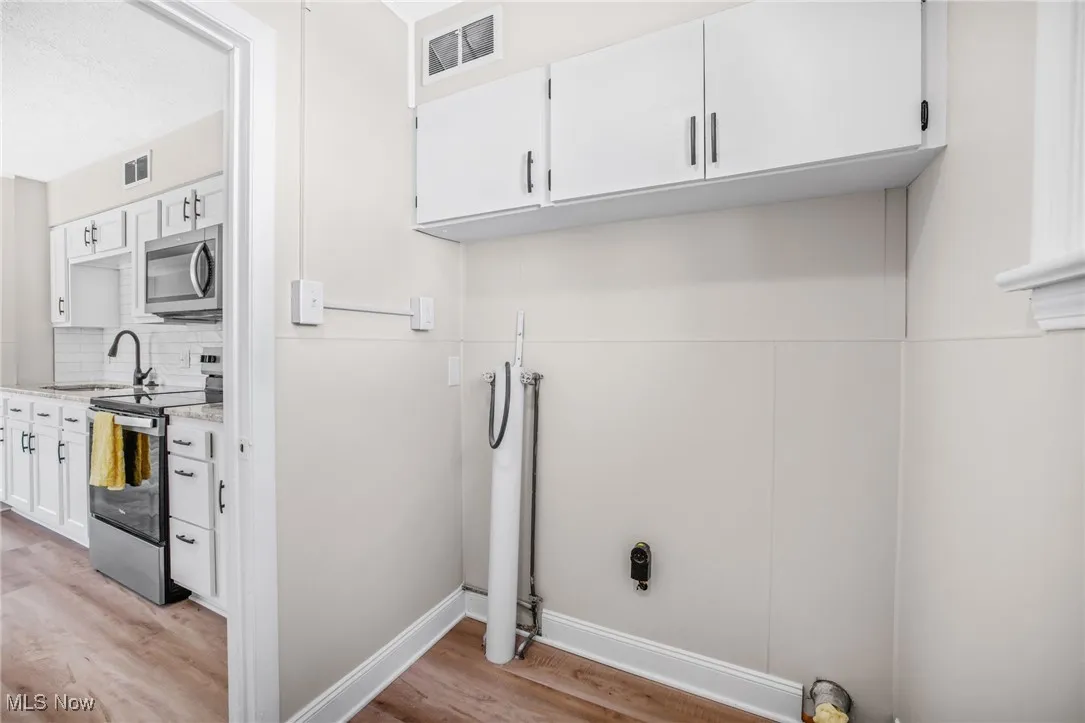 Washroom with light wood-type flooring, hookup for a washing machine, and cabinet space