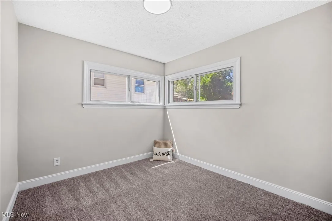 Carpeted spare room featuring a textured ceiling and baseboards
