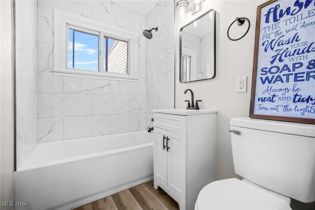 Bathroom featuring vanity, wood finished floors, and  shower combination