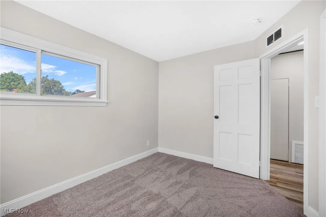Unfurnished bedroom with carpet flooring and baseboards