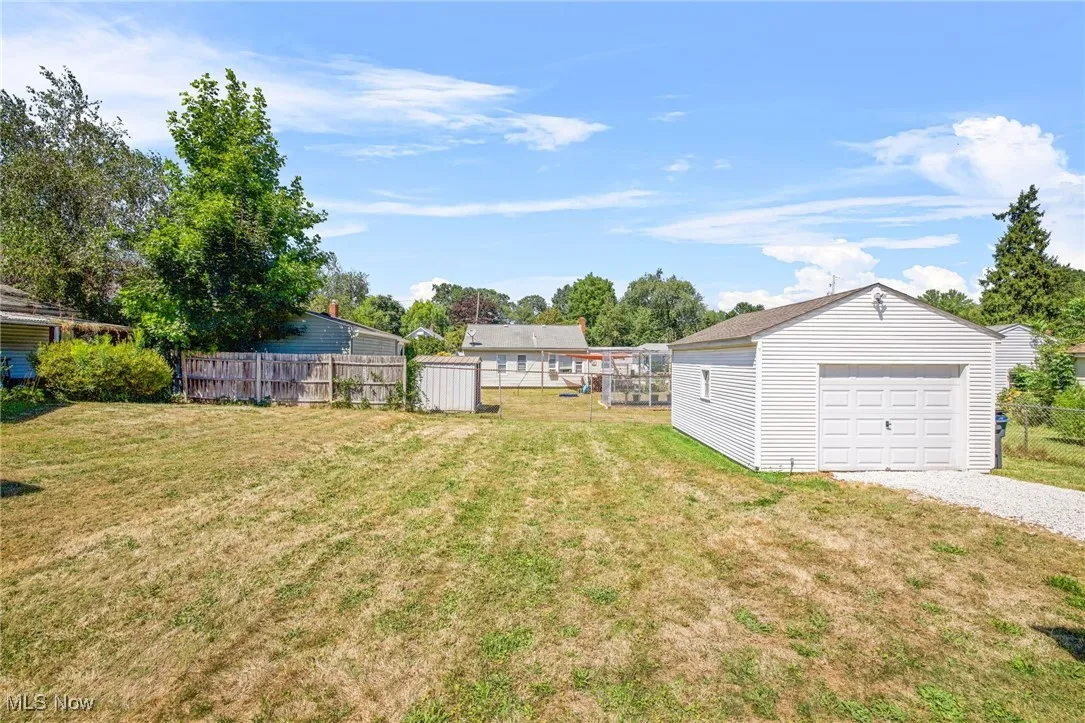 View of yard featuring a detached garage, driveway, and an outbuilding