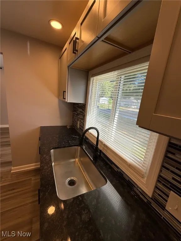 Kitchen with dark wood finished floors, dark stone counters, recessed lighting, and backsplash