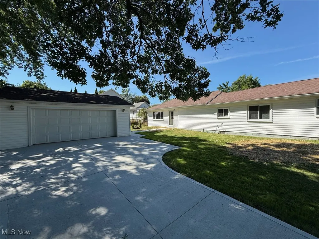 View of property exterior with an outdoor structure, a lawn, and a detached garage