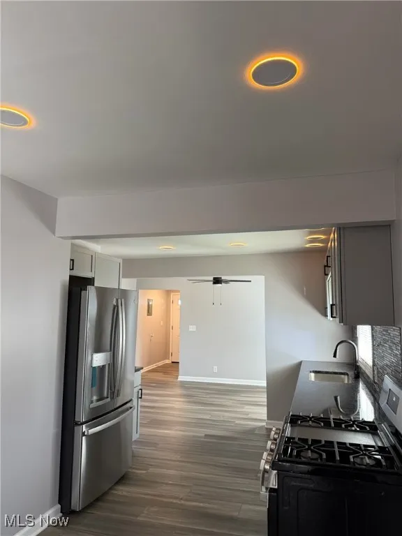 Kitchen featuring stainless steel appliances, dark wood-style floors, and dark stone counters