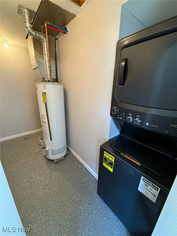 Washroom featuring stacked washing machine and dryer and water heater
