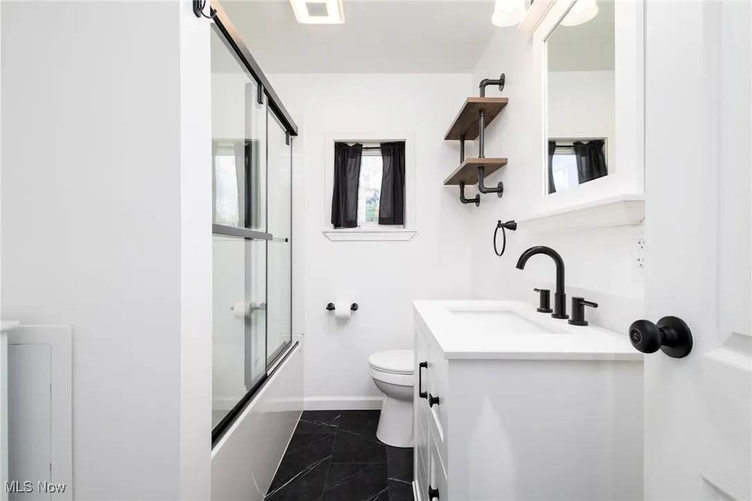 Full bathroom featuring bath / shower combo with glass door and vanity