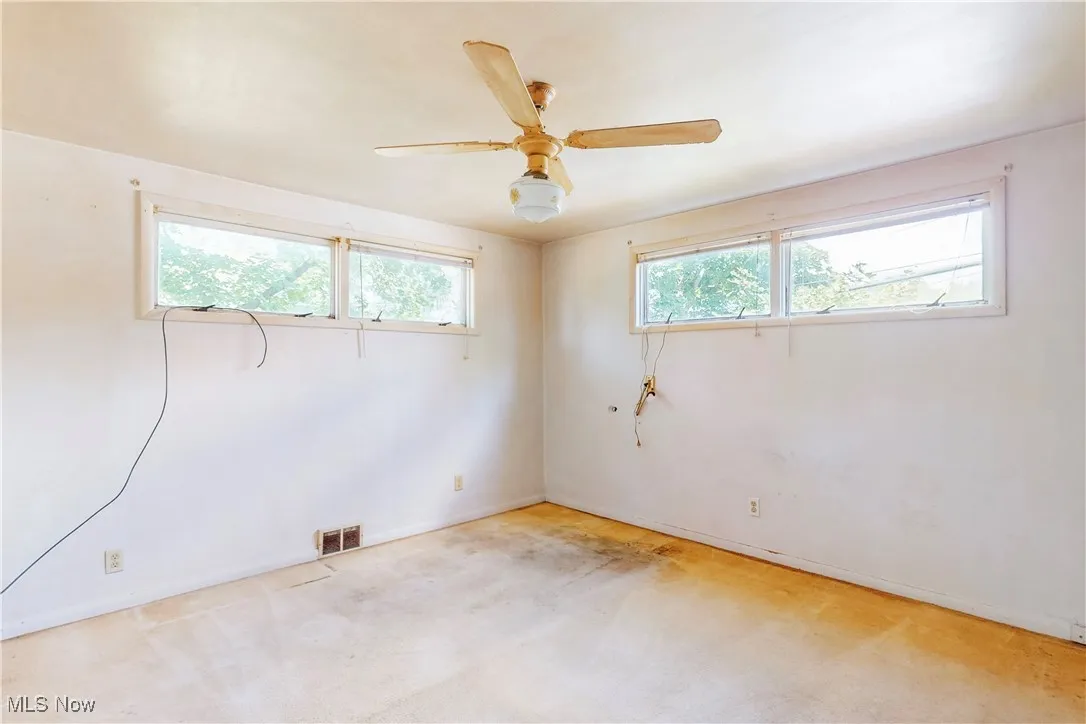Carpeted empty room with plenty of natural light and ceiling fan