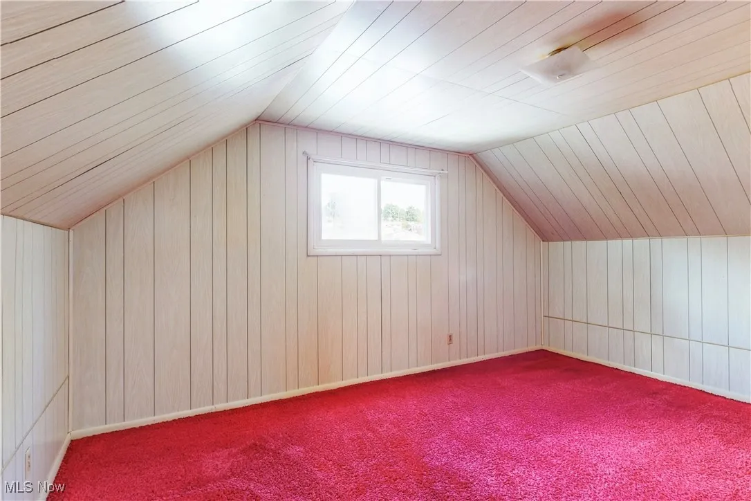 Bonus room featuring wood walls, lofted ceiling, carpet flooring, and wooden ceiling