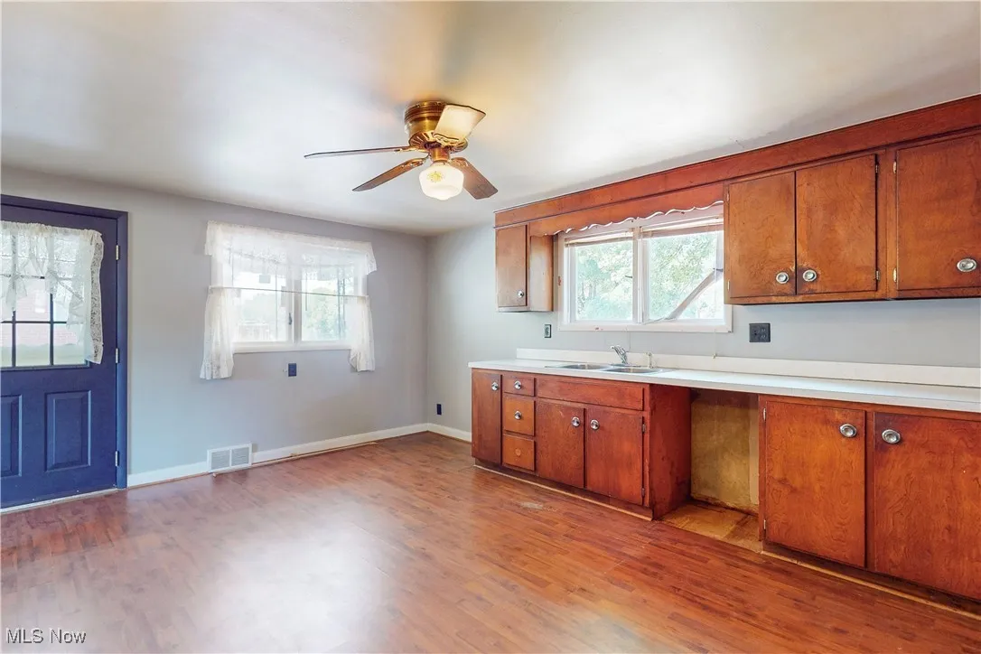 Kitchen featuring light countertops, dark wood-style flooring, brown cabinetry, and ceiling fan