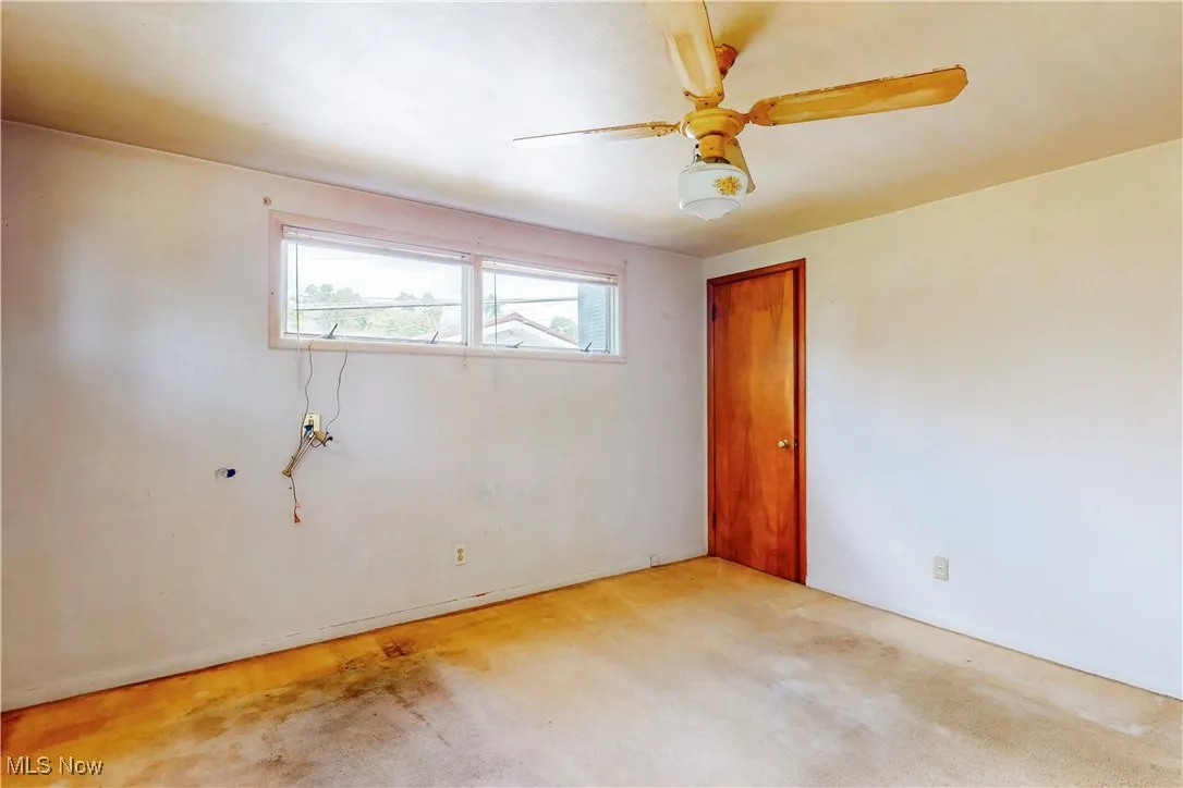 Empty room featuring ceiling fan and light carpet