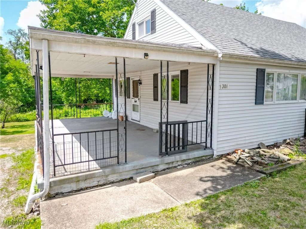 View of front of home with a porch, roof with shingles, and a carport